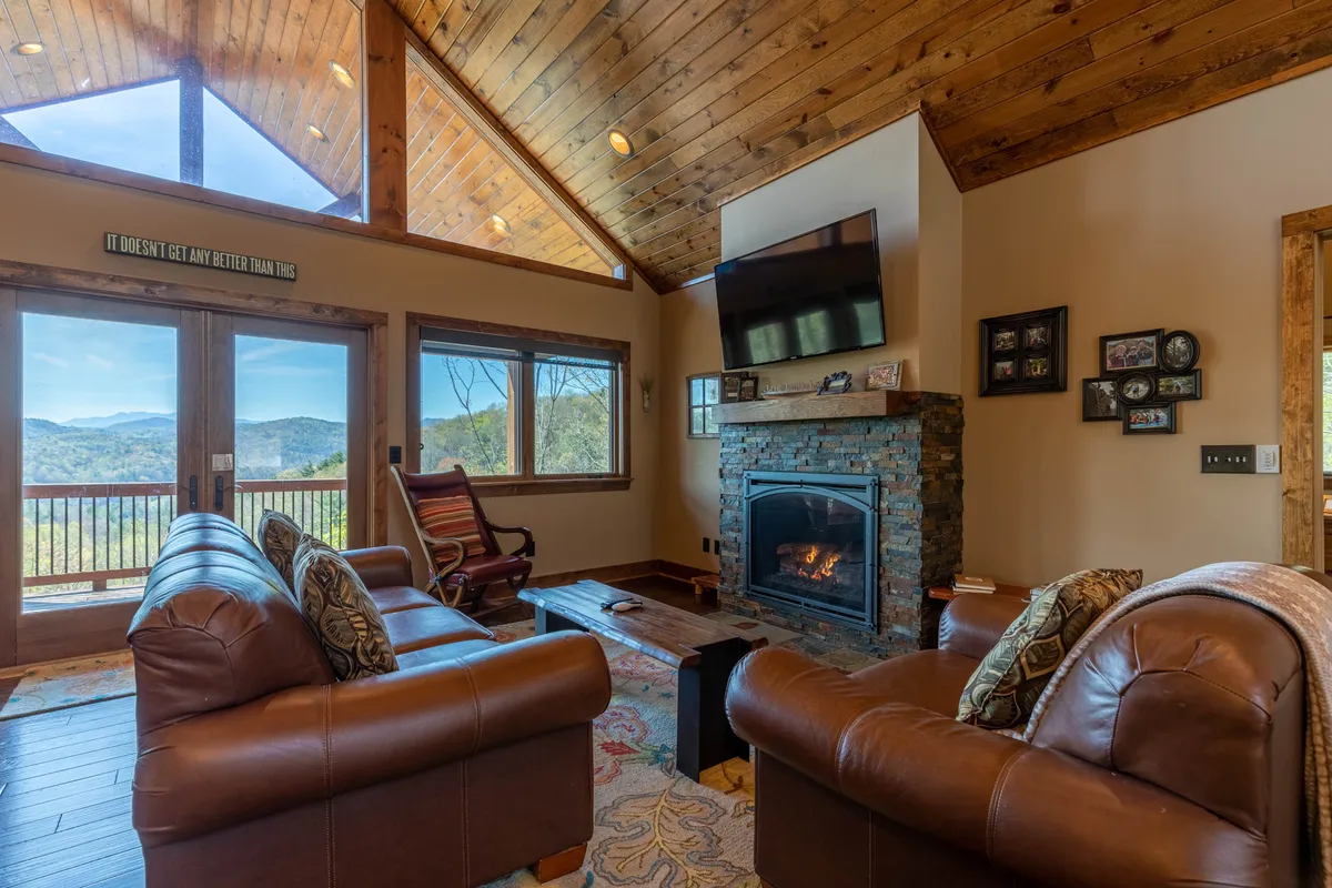 An inviting living room featuring a remote-controlled gas fireplace, large windows that frame the mountain landscape, and plush sofas arranged for relaxation. The setting is ideal for cozy evenings, intimate conversations, and appreciating the view.